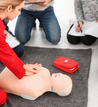 Woman demonstrating CPR on mannequin in first aid class