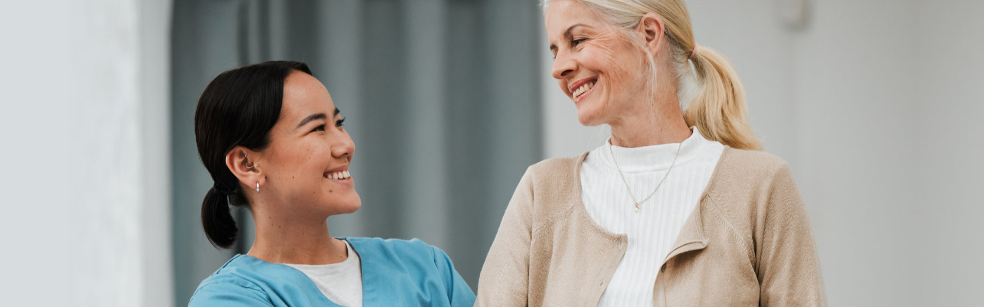 Elderly woman and female nurse smiling at each other