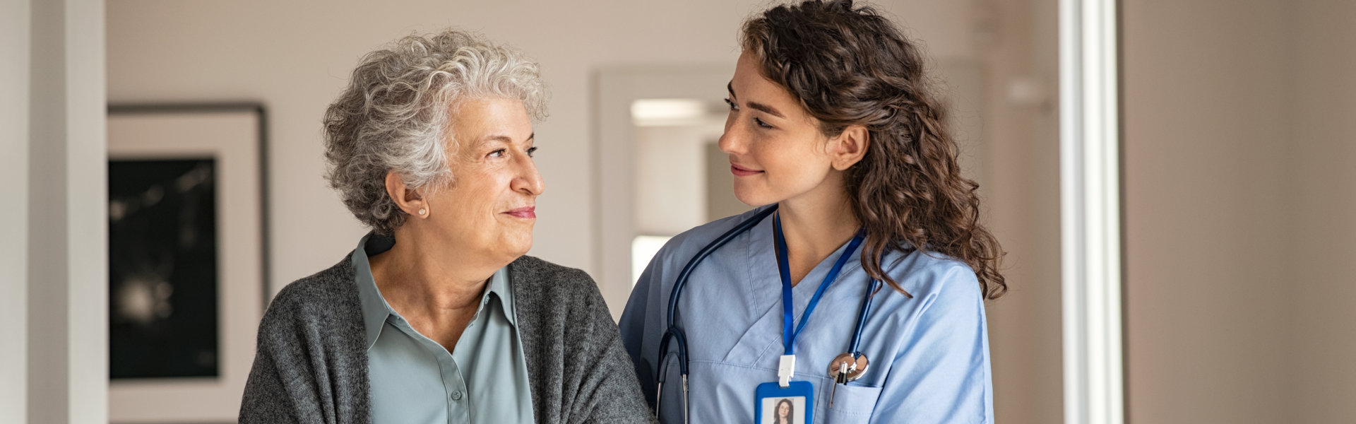 Elderly woman and female nurse looking at each other