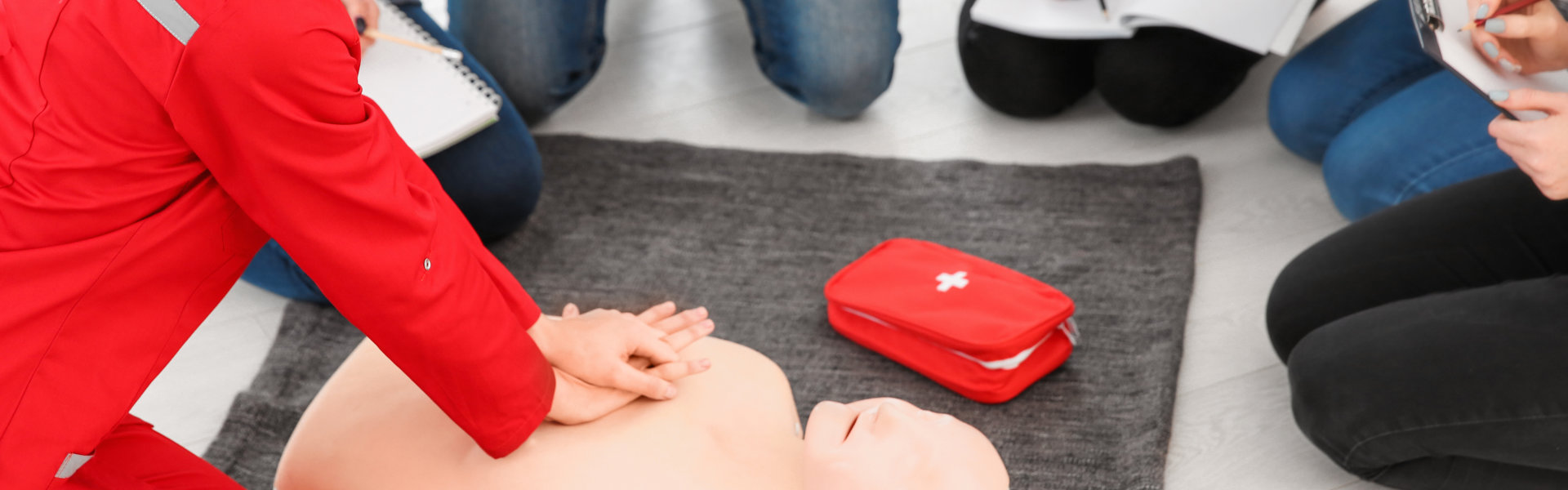 Woman demonstrating CPR on mannequin in first aid class